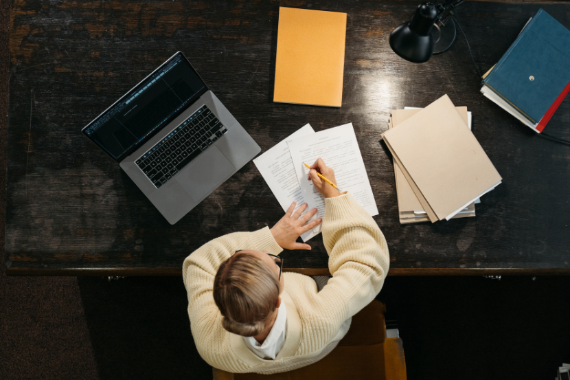 Overhead view of busy person surrounded by paperwork, symbolizing admin overload pulling time from billable work.