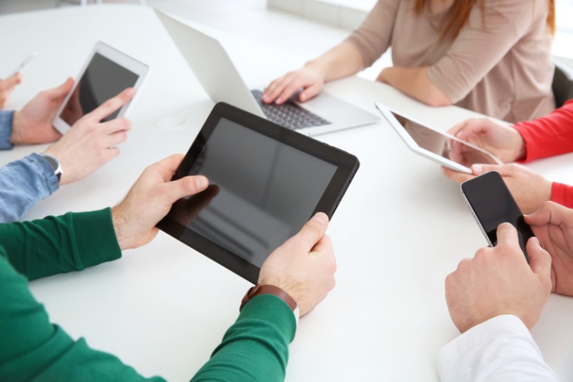 Team using multiple devices, symbolising inconsistent tools and fragmented workflows.