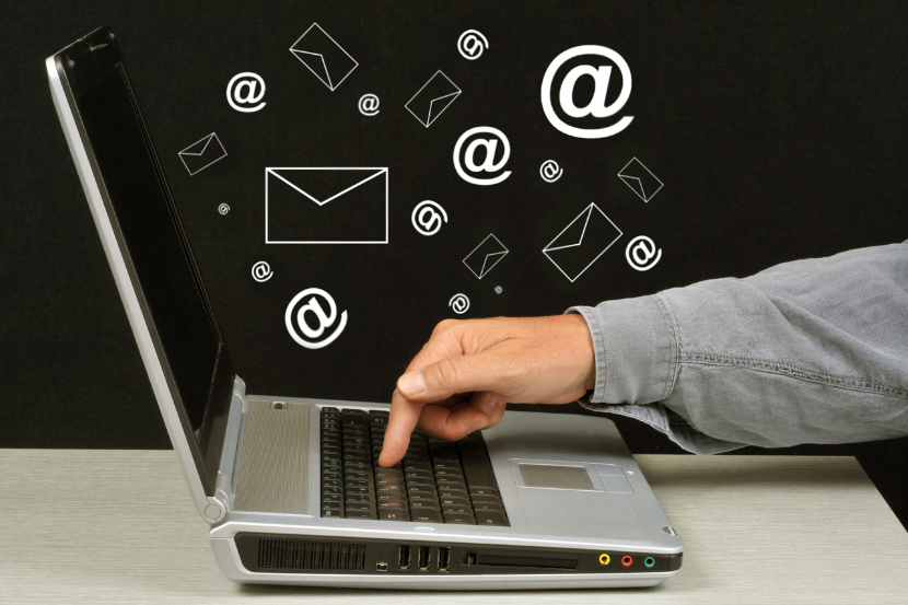 Hand reaching from laptop with scattered email icons, symbolising fragmented data across systems.